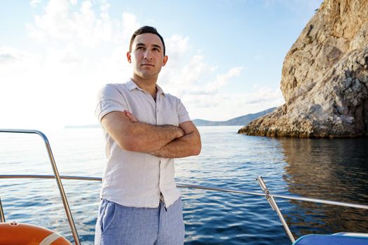 Young man in white shirt standing on the nose yacht in the open sea