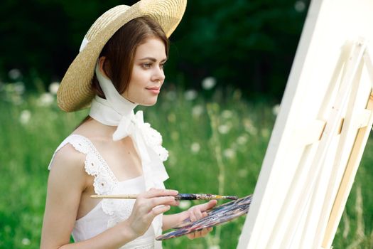 woman artist view with paint palette draws a picture in nature. High quality photo