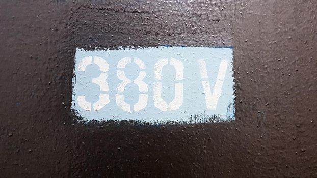 380 watts painted on gray metal cover of high voltage electrical panel