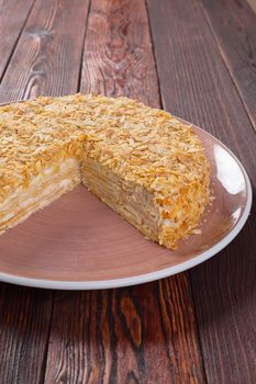 Cut caramel cake on plate on wooden table close up