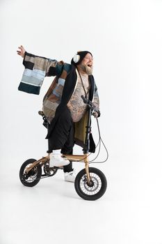 Big fat tattoed caucasian man in kimono is holding little bicycle and smilling