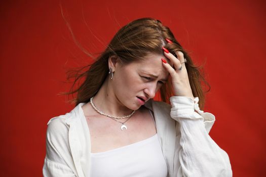 Displeased young woman in light clothes on a red background