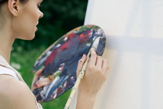 woman artist paints palette easel nature drawing. High quality photo