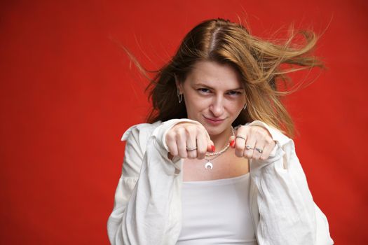 young girl shows comic boxing with fists in studio on red background