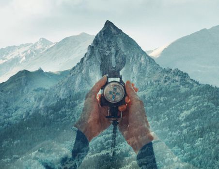 Double exposure image of mountain and female hands with hiking compass.
