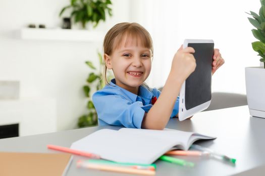 Smart little schoolgirl with digital tablet in a classroom. Child in an elementary school. Education and learning for kids.