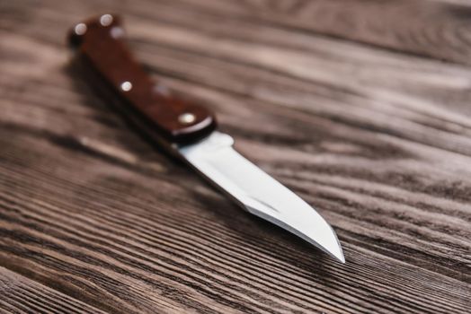 Stainless jackknife on a wooden background.