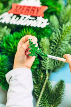 A girl draws a Christmas tree, preparing for the New Year 2022. Merry Christmas and happy new year concept