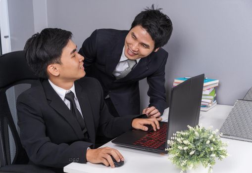 two business man laughing while using a laptop computer