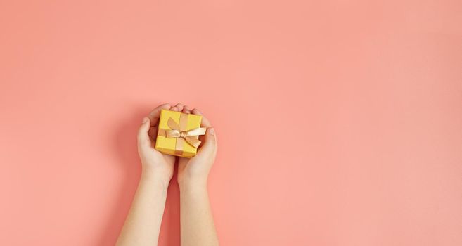 The child is holding a New Year's gift on a pink background with New Year's decorations.