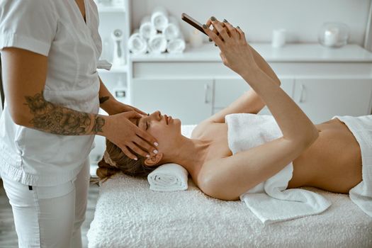 Therapist is doing face relaxing massage to a young woman in modern wellness cabinet