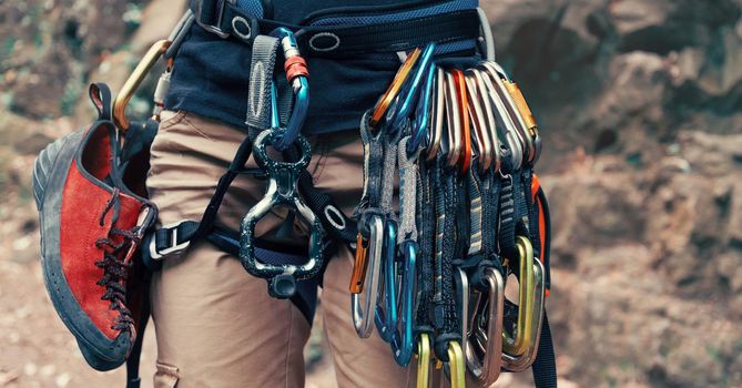 Unrecognizable climber young woman wearing in safety harness with climbing equipment outdoor