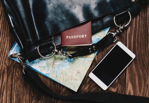 Bag with map and passport on wooden background, concept of travel.