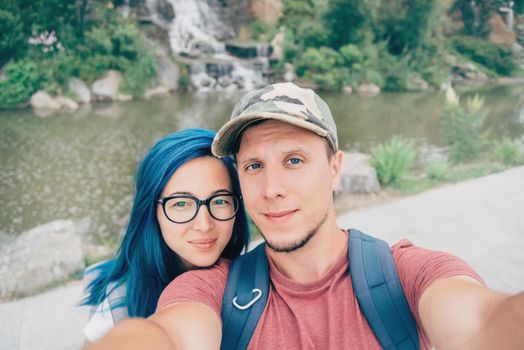 Traveler young loving couple taking selfie outdoor in summer. Girl with blue hair.