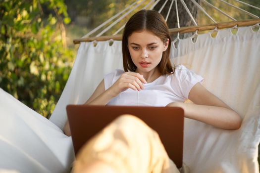 woman working in front of laptop in a hammock in nature. High quality photo