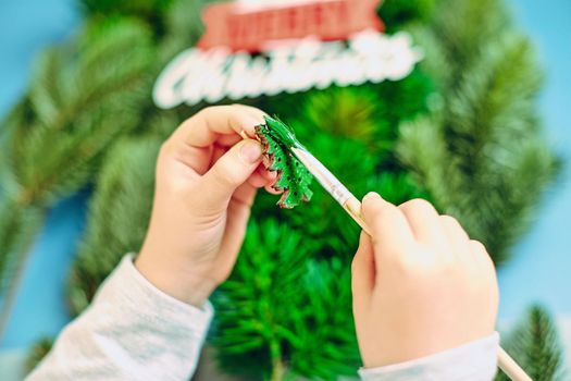 A girl draws a Christmas tree, preparing for the New Year 2022. Merry Christmas and happy new year concept