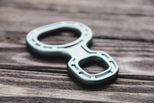 Climbing belay device figure eight on a wooden background, close-up.