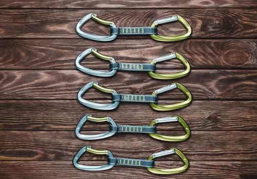 Climbing quickdraws on a wooden background, top view.