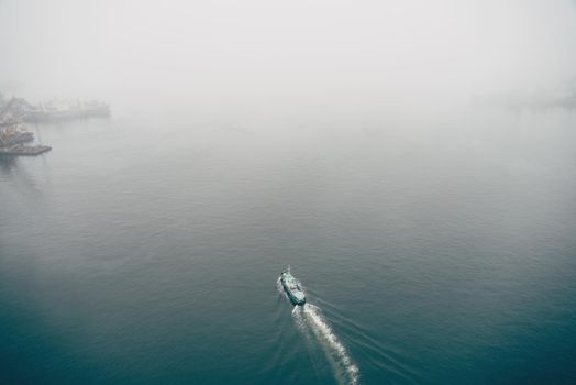 Motor boat sails on sea in foggy weather, top view. Copy-space.