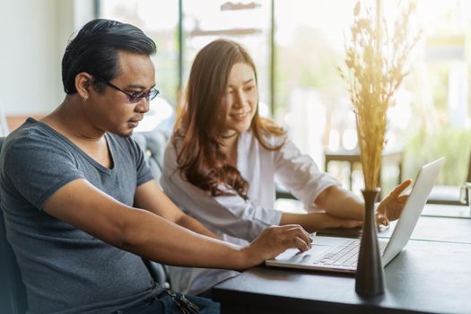 man and woman using laptop in a cafe