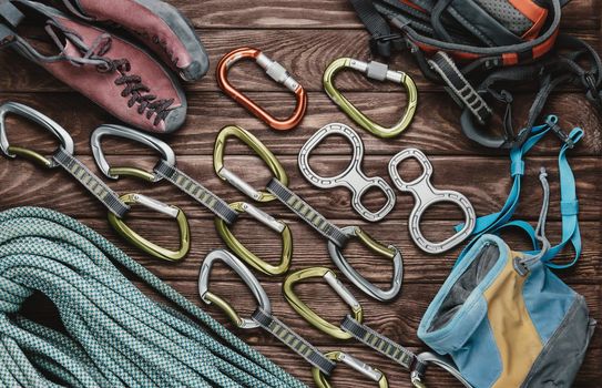 Set of equipment for climbing sport on wooden background, top view.