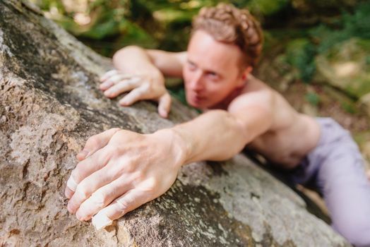 Young strong man climbing on rock boulder outdoor.