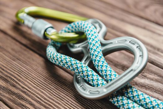 Climbing belay device with rope and carbine on wooden background.