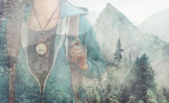 Double exposure image of female explorer with compass and mountain.