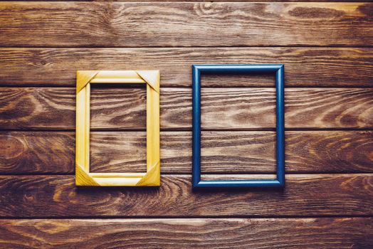 Two empty square frames on a dark wooden background, top view. Copy-space.