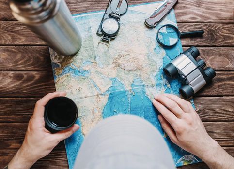 Unrecognizable man looking for a place to travel on map, point of view.