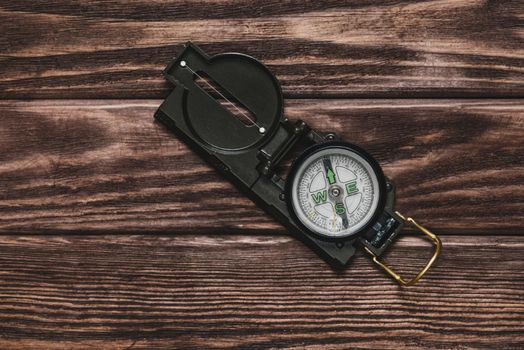 One compass on a wooden background, top view.