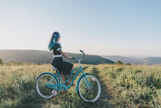 Girl sitting on cruiser bicycle and enjoying view of nature.