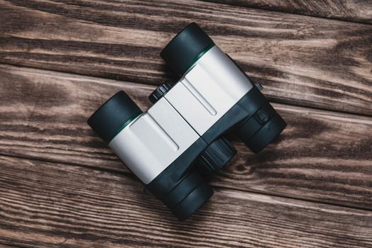 Tourism binoculars on a wooden background, top view.