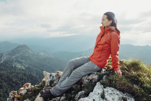 Hiker young woman resting on peak of mountain and enjoying view of nature in summer.