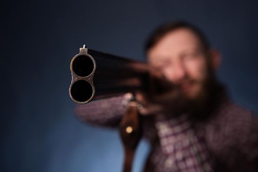 Man holding a shotgun on dark blue background.