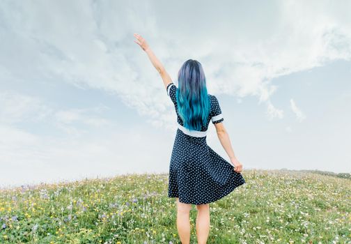 Young woman in dress waving her hand outdoor, rear view. Copy-space for text.