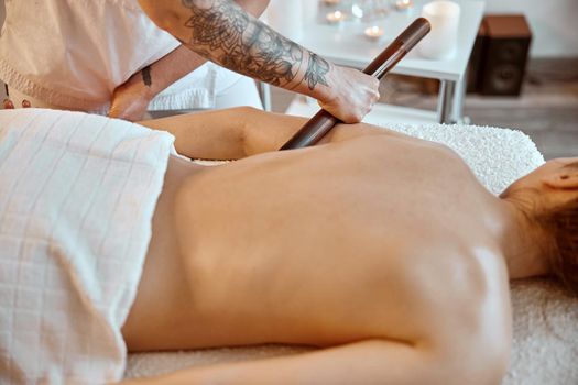 Professional confident massage master is doing procedures to caucasian woman in minimalistic modern cabinet