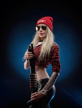 bright blonde in a red hat with a shotgun on a dark background