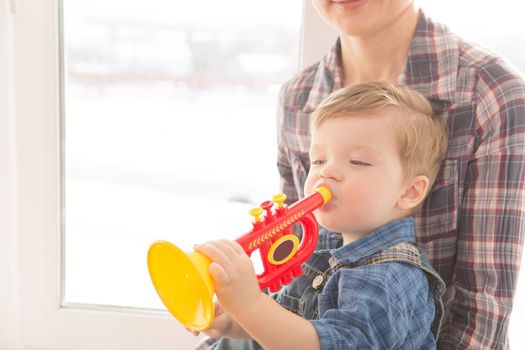 kid and mother play musical toys on a background of the window in the house. The concept of happiness and love.