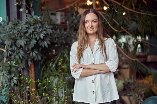 Confident female florist is posing and smiling in camera