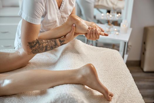 Professional confident massage master is doing procedures to caucasian woman in minimalistic modern cabinet