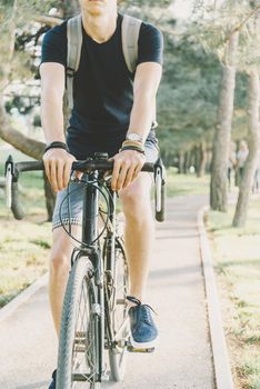 Young man riding on bicycle lane in summer park.