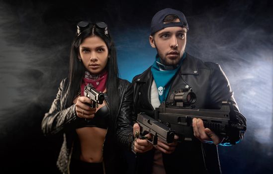the girl and a guy in a leather jacket with a gun