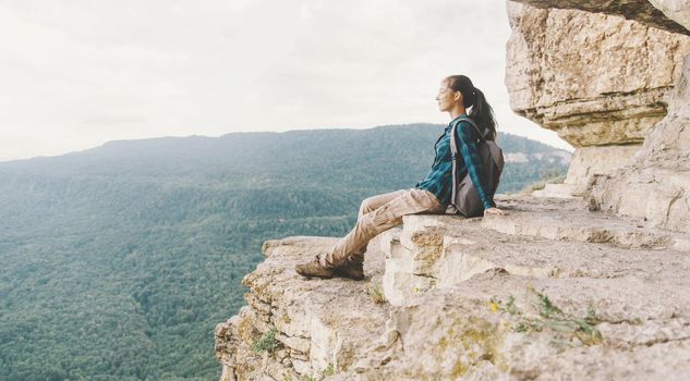 Traveler young woman resting on cliff Eagle shelf in summer, Mezmay, Krasnodar region, Russia.