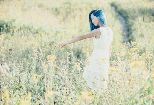Beautiful young woman walking on wildflower meadow in summer.