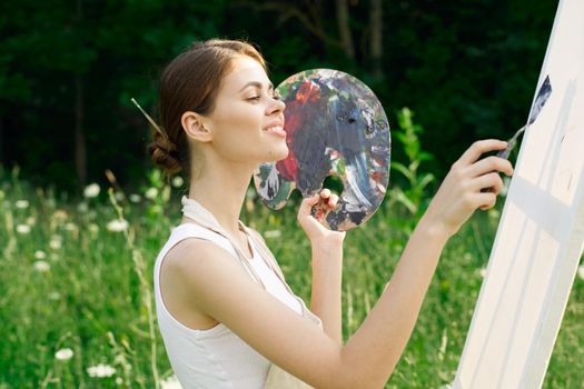 cheerful woman paints a picture palette nature landscape. High quality photo