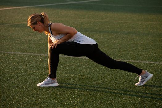 Sports girl doing stretching on the stadium lawn. High quality photo