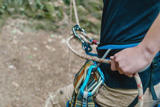 Unrecognizable female climber wearing in safety harness belaying with figure eight.