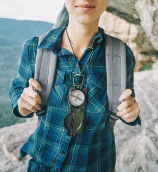 Backpacker young woman standing with compass outdoor.