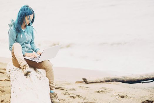 Freelancer girl sitting on beach and working on laptop near the sea. Freelance concept.